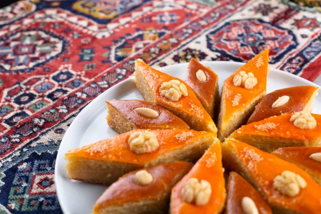 Aserbaidschanische traditionelle Novruz-Gebäcksorten Pakhlava und Shakarbura auf einem ethnischen Teppich zur Frühlingstagundnachtgleiche und Neujahrsfeier im März