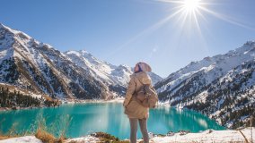 Frau erkundet Almaty See bei Sonnenschein zu Winterbeginn.