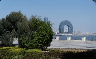 Curved building by the water with trees in foreground