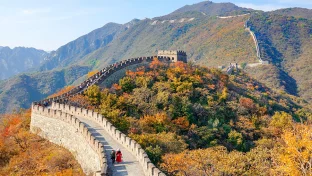 Zwei Touristen gehen auf einem Weg auf der Spitze der Chinesischen Mauer.