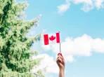 Nahaufnahme einer weiblichen Hand, die vor blauem Himmel eine kanadische Flagge schwenkt Nahaufnahme einer weiblichen Hand, die vor blauem Himmel eine kanadische Flagge schwenkt