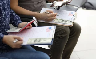 Nahaufnahme von Menschen, die Anträge für ein Visum für die USA ausfüllen